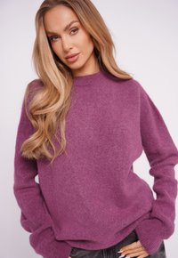 Purple, fuzzy knit sweater with a round neckline, dropped shoulders, and long sleeves, paired with dark jeans. Soft texture and relaxed fit.