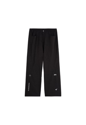 Pantalons noirs amples en tissu léger. Comprend des poches avant et des logos blancs sur le bas des jambes. Texture lisse.