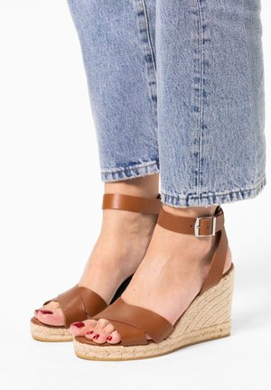 Braune Leder-Wedge-Sandalen mit überkreuzten Riemen und Knöchelverschluss, ausgestattet mit einer gewobenen Jute-Zwischensohle und einer Gummisohle.