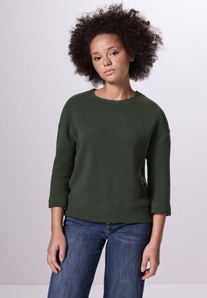 Groen, textuurtrui met een ronde halslijn en driekwartmouwen, gecombineerd met denim jeans. Zacht, casual ontwerp.