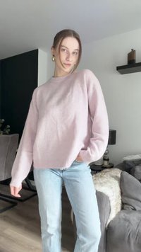 Light pink knitted sweater with a round neckline, ribbed cuffs, and hem; paired with light blue straight-leg jeans.