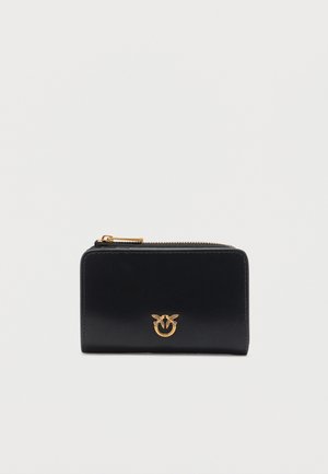 Portafoglio in pelle nera con cerniera dorata e un piccolo emblema dorato di due uccelli su un anello al centro frontale.