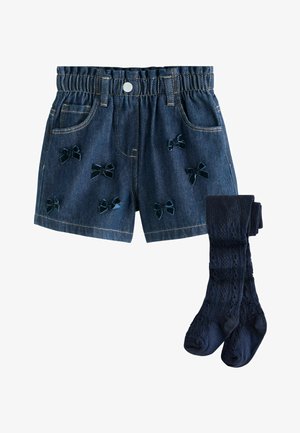 Jeanske kratke hlače v temno modri barvi, okrašene z raztresenimi aplikacijami iz žametnih pentelj; v kombinaciji z usklajenimi teksturiranimi temno modrimi nogavicami do kolen.