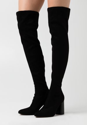 Bottes cuissardes en daim noir avec une coupe ajustée, un bout pointu et un talon épais. Texture lisse et conception sans couture sans éléments métalliques visibles.