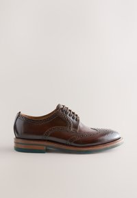 Scarpa elegante da uomo in pelle marrone con dettagli brogue, punta arrotondata e design con lacci. Presenta una suola di colore marrone chiaro a contrasto con un accento blu.