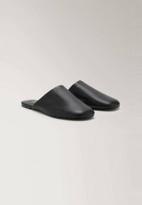 Mules de cuero negro con punta afilada y diseño minimalista. Textura suave, suela plana, sin hardware visible y con parte trasera abierta.