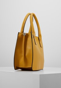 Borsa a tracolla gialla in pelle con un design strutturato, caratterizzata da bordi neri, due manici rotondi e una chiusura con zip argentata nella parte superiore.