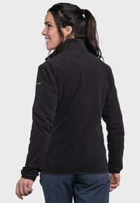 Schwarze Fleecejacke mit hohem Kragen, langen Ärmeln und glatter Textur. Verfügt über dezente Nähtdetails. Eignet sich gut zum Schichten.