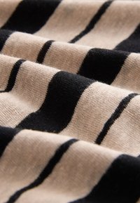 Pleteni material z izmeničnimi črnimi in rjavimi progami, z mehko teksturo in vidnim finim vzorcem pletenja. Rahlo bleščanje na določenih mestih.
