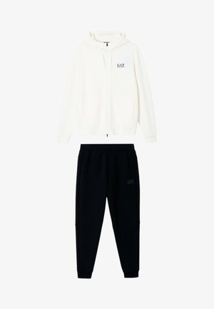 Felpa bianca con cappuccio e zip con logo EA7 abbinata a pantaloni jogger neri con logo EA7 sulla tasca.