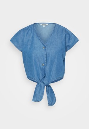 Top de denim azul con escote en V, mangas cortas y un dobladillo anudado en la parte delantera. Cuenta con dos botones y una tela ligeramente texturada.