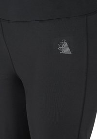 Black leggings made of stretchy material with a sleek, smooth texture. Features a reflective logo and flat seams for comfort and style.