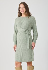 Rochie de maternitate tricotată verde, cu mâneci lungi, textură cu nervuri și o curea asortată la talie, lungime până la genunchi.