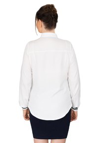White long-sleeve shirt with a structured collar, featuring a curved hem and contrasting black accents on the cuffs. Smooth fabric texture.