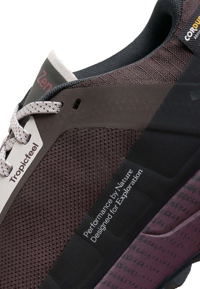 Baskets brun foncé avec tige en maille et accents gris. Présentent des lacets gris, un col rembourré et une semelle extérieure noire texturée avec des détails de marque.