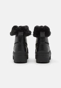 Black ankle boots with a textured synthetic upper, faux fur collar, and rubber sole. Features pull tab at the back for easy wear.