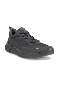 Black athletic shoe with mesh upper, textured accents, and padded collar. Features a contour sole, reflective laces, and supportive design.