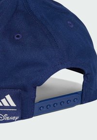 Navy blue cap with a textured fabric, featuring a white logo on the side, adjustable snap closure, and stitching detail near the crown.