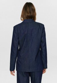 Dark denim blazer with a tailored fit, featuring a notched collar, long sleeves, and subtle texture. Back view shows clean lines and structure.