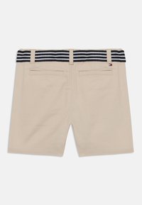 Shorts beige avec une ceinture à rayures bleu marine, dotés de deux poches arrière et d'une étiquette logo. Tissu lisse avec une coupe ajustée.