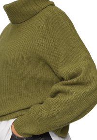 Olijfgroene gebreide trui met een hoge funnelnek en oversized mouwen. Zachte textuur en ribbelstructuur op de kraag en manchetten.