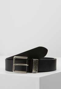 Black leather belt featuring a silver metal buckle with an engraved "Armani Exchange" logo. Smooth texture, minimalist design, and a classic shape.