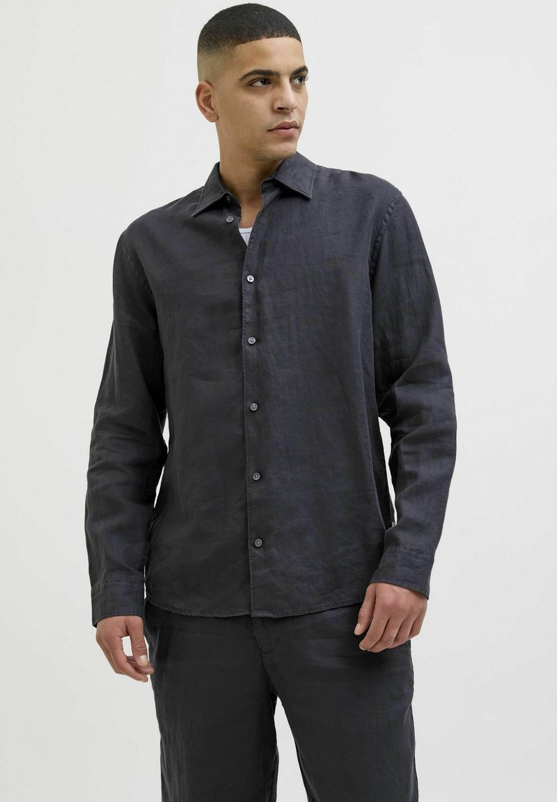 Camisa de lino azul oscuro con un corte relajado, mangas largas y cuello clásico. Presenta cierre de botones y una textura sutil.