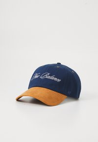 Navy cap featuring a suede orange brim, embroidered "New Balance" logo in white, and metal eyelets for ventilation.
