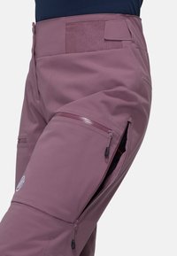 Purple waterproof pants featuring zippered side pockets, a smooth texture, and a tailored fit. Made from durable, flexible material.