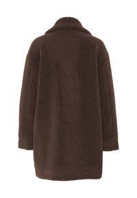 Pruun, ülepaisutatud villane mantel pehme ja tekstuurse pinnaga. Omab kleepuvat kaelust ja madalaid õlgu, et saavutada mugav istuvus.