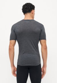 Graues, eng anliegendes T-Shirt mit kurzen Ärmeln aus leichtem, strukturiertem Stoff. Rundhalsausschnitt und leicht abgerundeter Saum auf der Rückseite.
