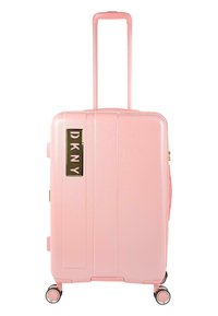 Maleta rígida rosa con ranuras verticales, asa retráctil, cuatro ruedas y un logotipo dorado de DKNY en el lateral. Textura lisa.