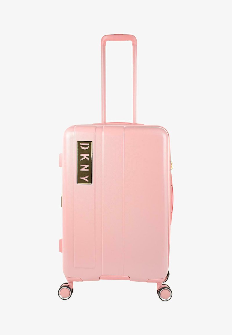 Maleta rígida rosa con ranuras verticales, asa retráctil, cuatro ruedas y un logotipo dorado de DKNY en el lateral. Textura lisa.
