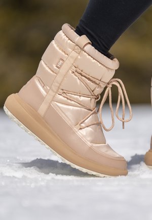 Lichtbeige, geïsoleerde winterlaars met een zachte, glanzende textuur, voorzien van een vetersysteem, een gevoerd schacht en een robuuste rubberen zool voor grip.