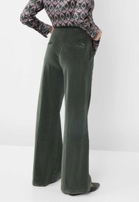 Pantalons larges en tissu vert doux, avec une texture lisse, deux poches arrière et un design taille haute.