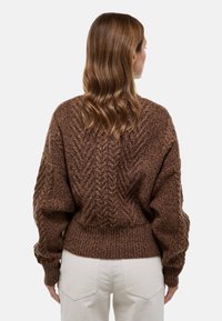 Pull en tricot marron avec un motif zigzag texturé, silhouette surdimensionnée et taille côtelée. La vue de dos montre des manches longues et une coupe décontractée.