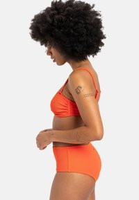 Geribbeld oranje bikini set met een gestructureerde bh-top en hooggetailleerde onderkant. Voorzien van verstelbare bandjes en een naadloze afwerking.