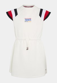 Weißes Kleid mit kurzen Raglansleeves in Rot, Weiß und Marineblau. Verfügt über einen elastischen Kordelzug in der Taille und ein farbenfrohes gesticktes Logo auf der Brust.