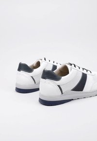 Baskets blanches avec des matériaux en maille et en cuir, présentant des accents bleu marine, un bout arrondi, un design à lacets et une semelle texturée.
