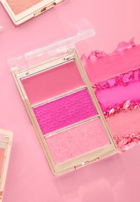 Trikolors rougepalett med genomskinlig lock. Innehåller mjuk rosa, stark rosa med texturerad design och ljusrosa puder i ett guld-accentuerat etui.