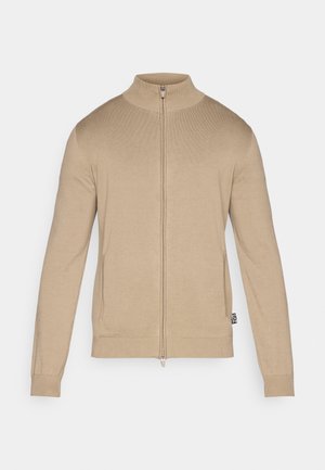 Beige trui met rits en opstaande kraag, lange mouwen, geribde manchetten en zoom, met een gladde textuur en subtiel merkdetail aan de zijkant.