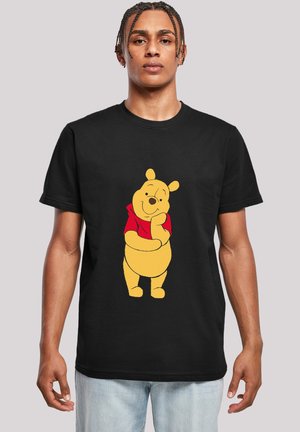 Black t-shirt featuring a yellow cartoon bear with a red shirt, smiling and standing with one hand on its chin, against a gray background.