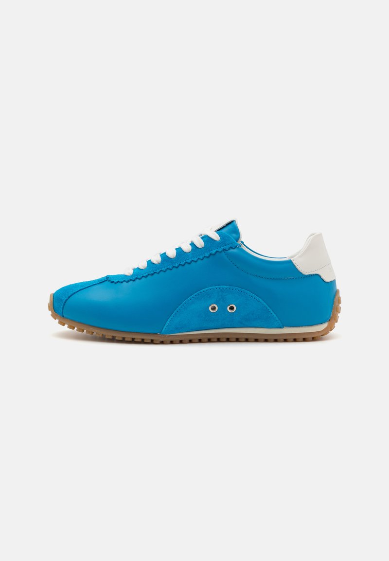 Pantofi sport din piele albastră cu o textură netedă, accente albe și talpă din cauciuc maro. Prezintă cusături decorative și ochiuri din metal.