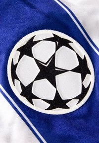 Zwart-wit voetbalsymbool met vijf zwarte sterren op een cirkelvormige witte achtergrond, geplaatst op een blauw-witte stoffen ondergrond.
