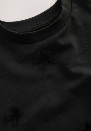 Tissu noir avec un col rond et trois petits noeuds texturés espacés uniformément sur le devant.