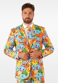 Kleurrijk pak gemaakt van gladde stof, met een patroon van cartoonwezens in oranje, groen en blauw, met een bijpassende stropdas.