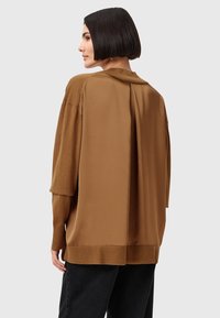 Maglione bicolore marrone in tessuto morbido, con retro liscio e maniche testurizzate, design con schiena aperta e orlo a costine.
