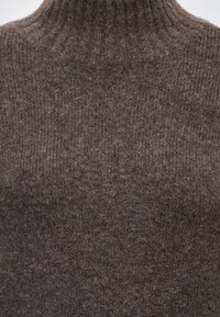 Pull à col roulé en maille marron avec une texture douce et duveteuse et un motif en côtes autour du cou et des épaules.
