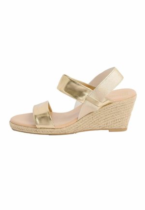 Zelta krāsas pacēluma sandale ar divām siksnām, vienu elastīgu potītes siksniņu un pītā jūtas platformas papēdi.