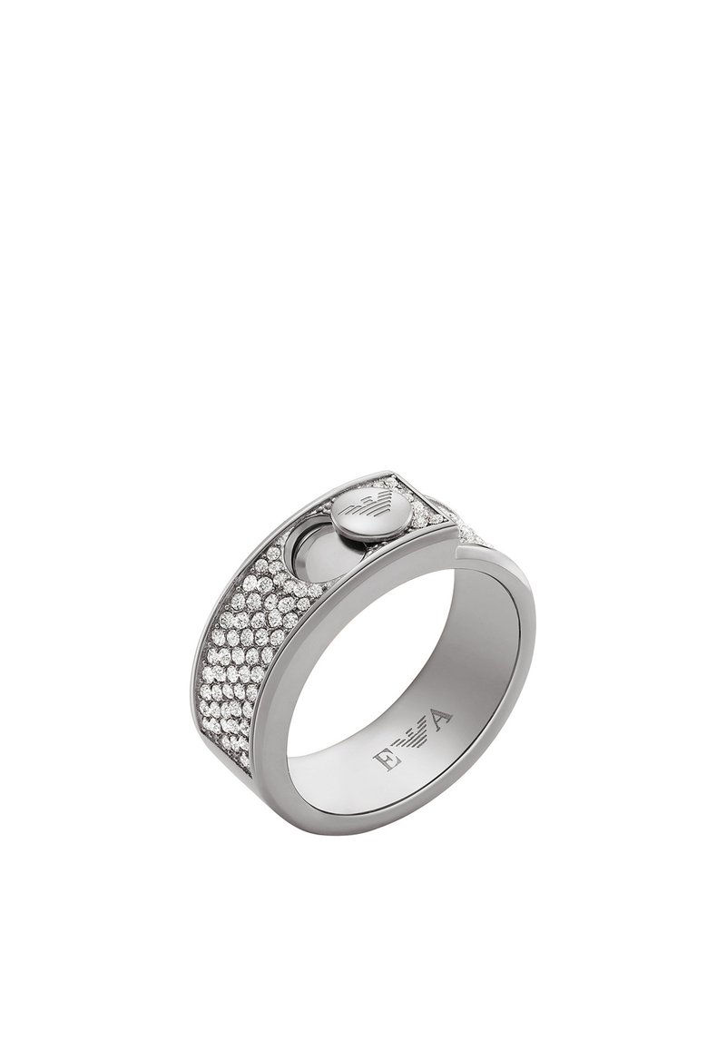 Silverring med en slät band, dekorerad med en rad klara kristaller och ett litet cirkulärt emblem på sidan.